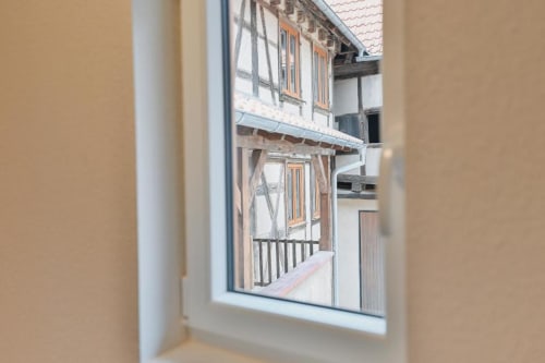 Vue par la fenêtre d'un bâtiment à colombages au Petit Havre de Joy, Dambach la Ville