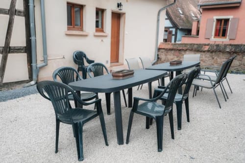 Zone de restauration extérieure du Petit Havre de Joy à Dambach-la-Ville avec table et chaises noires dans la cour pavée