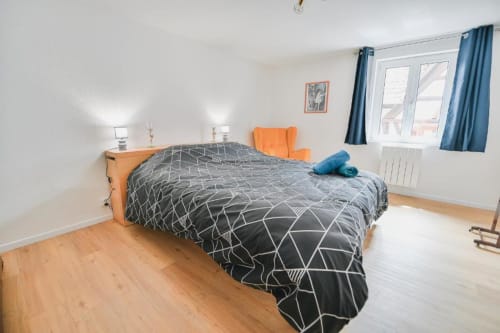 Chambre spacieuse de l'appartement Le Petit Havre de Joy à Dambach la Ville, avec lit queen-size, fauteuil orange et parquet