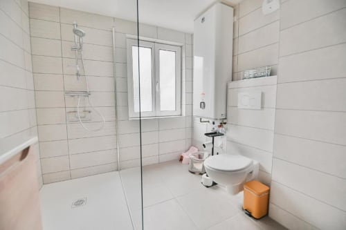 Salle de bain moderne avec douche à l'italienne, toilettes et carrelage blanc dans l'appartement Le Petit Havre de Joy, Dambach-la-Ville