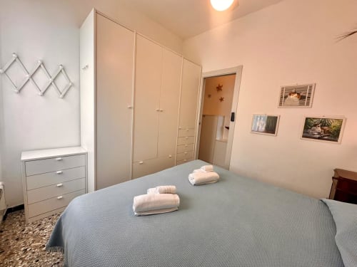 Camera luminosa al Welcome Varigotti. Letto matrimoniale con asciugamani, armadio, cassettone e quadri con vista sul mare.