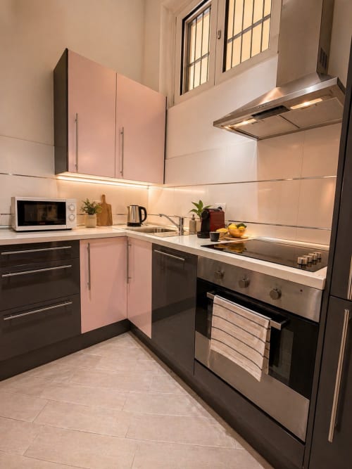 Modern kitchen in Loft 46 at Hb Hall Milano with pink cabinetry, stainless steel appliances, and ambient lighting