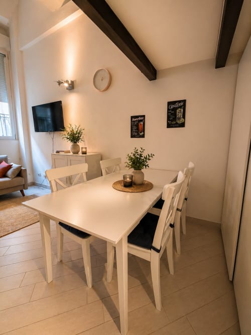 Modern dining area in Loft 46 at HB Hall Milano with white table, chairs, and city view apartment