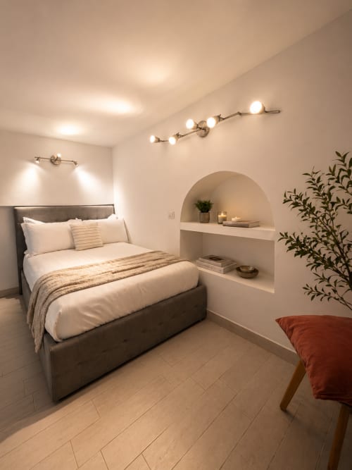 Modern loft bedroom at HB Hall Milano with gray bed, built-in niche shelving, pendant lights, and city view