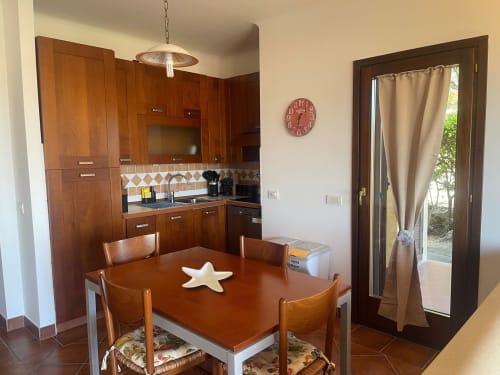 Modern kitchen and dining area at Like at Home Palau with wooden cabinets, dining table, and garden door view