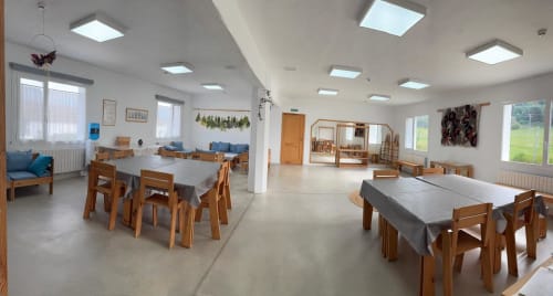 Luminoso comedor y espacio común del Rural B&B Entheos en Lerín con mesas de madera, sillas e iluminación moderna en el techo