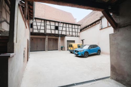 Cour intérieure avec voiture bleue à l'appartement Le Petit Havre de Joy à Dambach la Ville, bâtiments à colombages