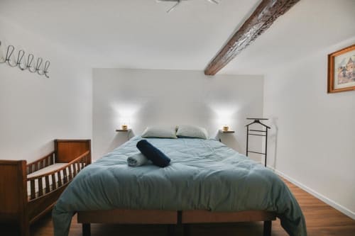 Chambre cosy au Petit Havre de Joy à Dambach la Ville avec literie bleue, poutres apparentes et charme rustique.