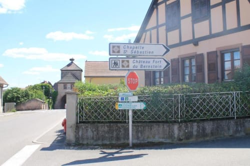 Charmant bâtiment à colombages à Dambach-la-Ville avec panneaux directionnels vers la Chapelle St Sébastien et le Château Fort