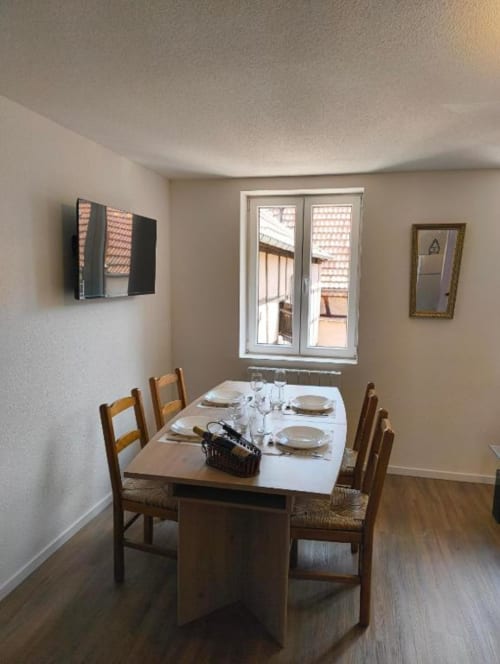 Coin repas de l'appartement 2 chambres au Petit Havre de Joy, Dambach la Ville, table dressée et vue sur le jardin