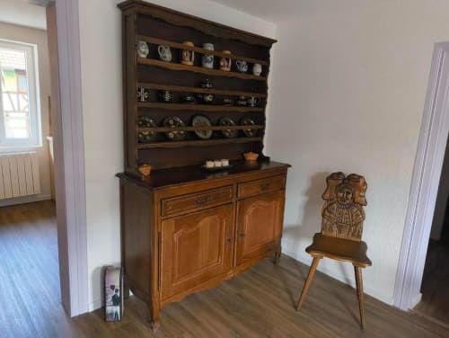 Buffet ancien en bois avec assiettes décoratives et petite chaise en bois à l'appartement Le Petit Havre de Joy, Dambach la Ville.