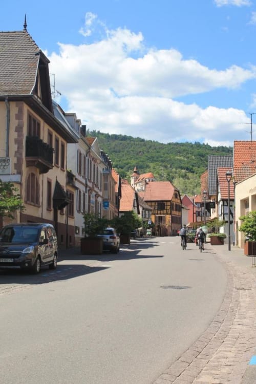 Charmante rue pavée de Dambach-la-Ville avec architecture alsacienne traditionnelle et collines boisées
