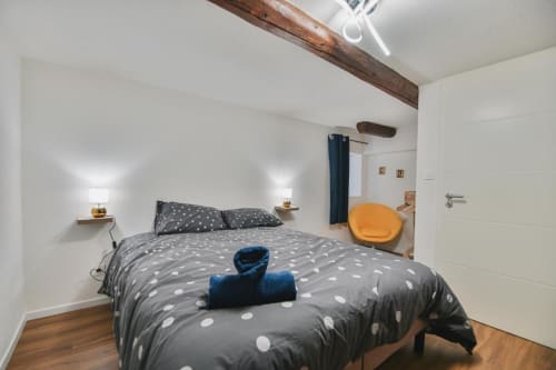 Chambre élégante de l'appartement Le Petit Havre de Joy à Dambach-la-Ville avec literie à pois, poutres en bois et coin détente douillet