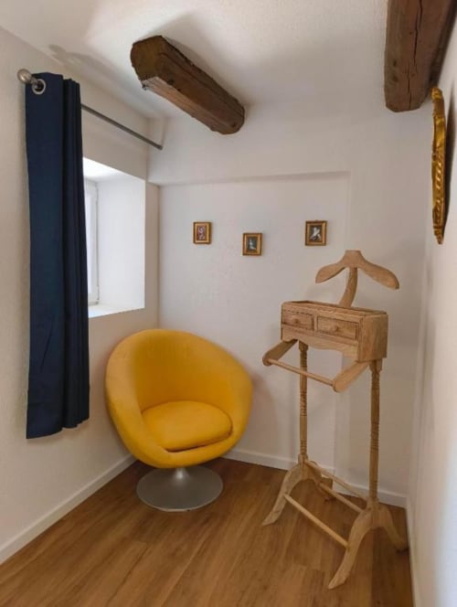 Chambre cosy au Petit Havre de Joy avec fauteuil jaune, portant en bois et poutres apparentes à Dambach
