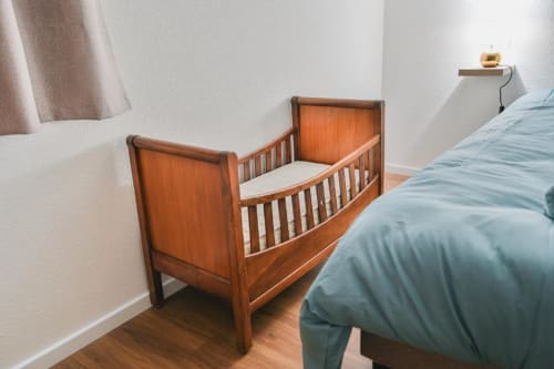 Lit bébé en bois avec matelas blanc à côté du lit des parents dans l'appartement 2 chambres au Petit Havre de Joy, Dambach-la-Ville