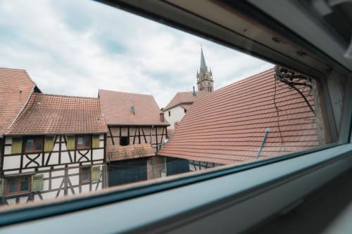 Maisons à colombages médiévales et clocher d'église du village alsacien de Dambach-la-Ville vus par la fenêtre
