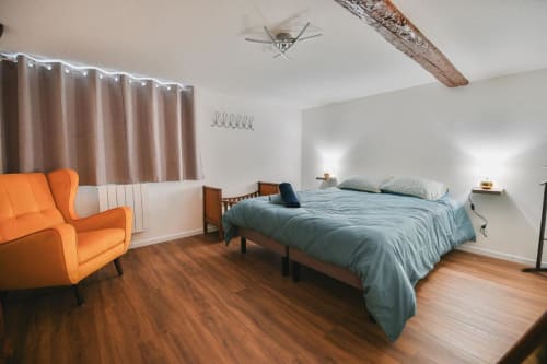 Chambre spacieuse du Le Petit Havre de Joy B&B à Dambach-la-Ville avec lit, fauteuil orange et poutres en bois