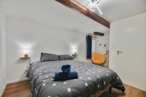 Chambre moderne au gîte Le Petit Havre de Joy à Dambach la Ville avec parure grise à pois, poutres en bois et style contemporain