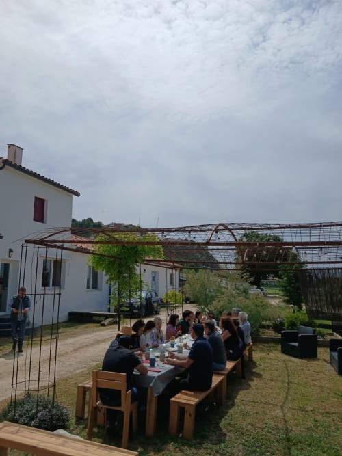 Área de comedor al aire libre en Entheos Rural de Lerín con huéspedes reunidos bajo una rústica pérgola