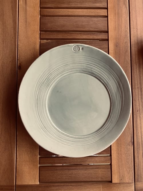 Elegante plato de cerámica blanca con patrón de espiral sobre mesa de madera en Casale Artemisia, Capalbio