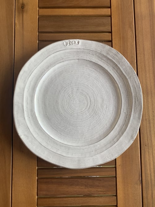 Plato de cerámica blanca con patrón espiral sobre superficie de madera en Casale Artemisia, Capalbio