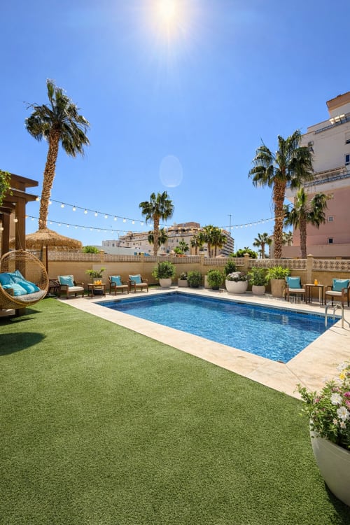 Piscina de lujo en la azotea de Sinese Design Homes en Málaga con palmeras, tumbonas y vistas al mar