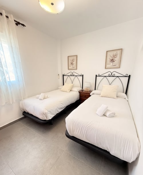 Camas gemelas con sábanas blancas en moderno apartamento malagueño de Sinese Design Homes