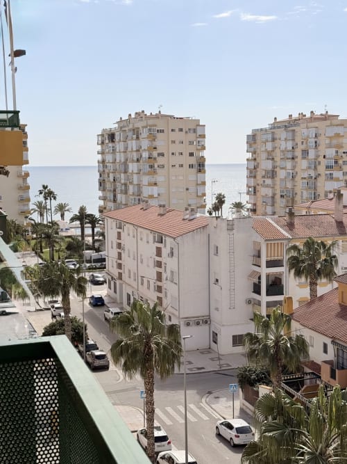 Edificio de apartamentos en la costa de Málaga con vistas al mar, palmeras y arquitectura mediterránea frente a la playa