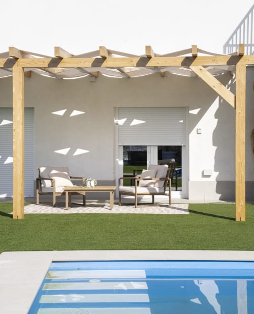 Pérgola de madera con zona de descanso con vistas a la piscina y lago en apartamento de Málaga