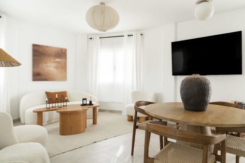 Moderno espacio de vida con mesa de comedor de madera, asientos color crema, televisión de pantalla plana y vistas al lago en Málaga, España