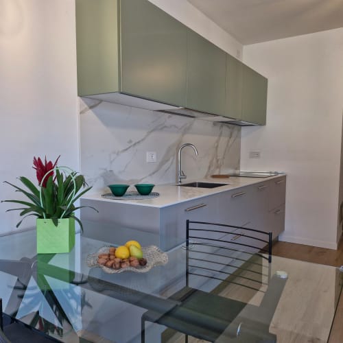 Cuisine moderne dans l'appartement La Casa di Silvia à Arco, avec armoires vert sauge, crédence en marbre et coin repas