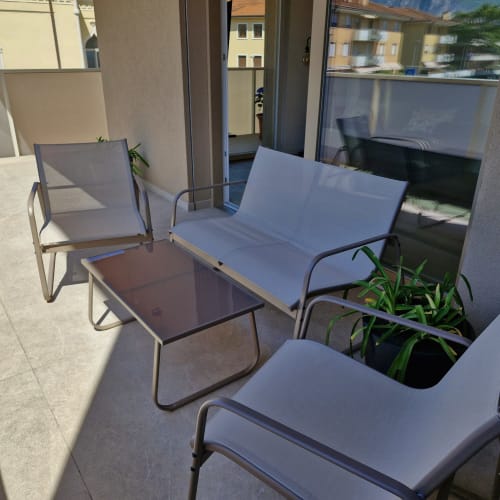 Terrasse aménagée de La Casa di Silvia avec chaises bleues, canapé, table et vue sur les montagnes à Arco, Italie