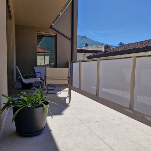 Terrasse ensoleillée de La Casa di Silvia avec vue montagne, plantes en pot, chaises longues et écrans de confidentialité dominant Arco,