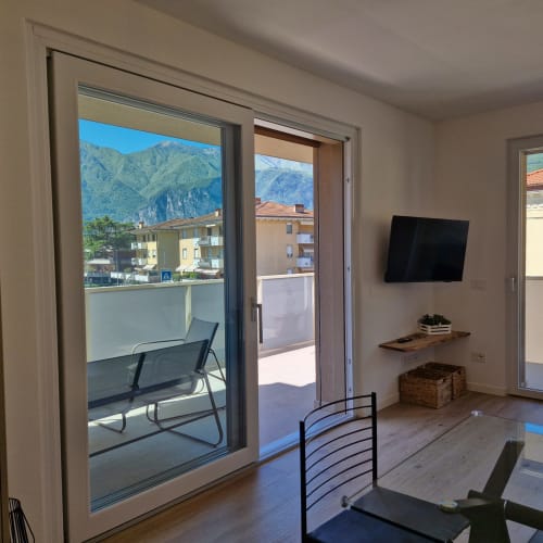 Salon moderne avec vue sur les montagnes du Trentin, téléviseur, accès au balcon et vue sur les Dolomites du Garda