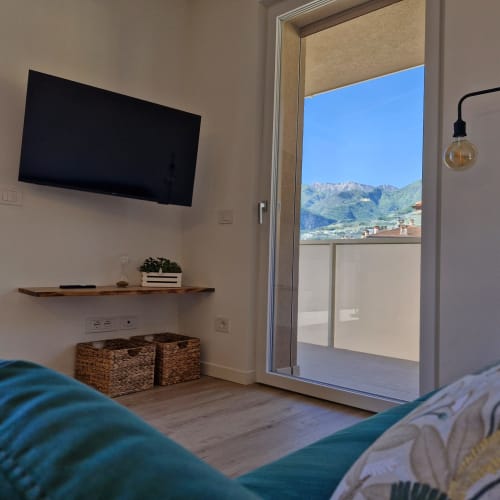 Chambre moderne à La Casa di Silvia avec vue sur les montagnes d'Arco, Italie. TV écran plat, étagère bois et terrasse