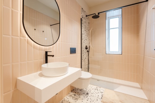 Salle de bain moderne de l'auberge Le Falcoz à Saint-Jean-de-Maurienne avec lavabo rond, robinetterie noire et sol en terrazzo