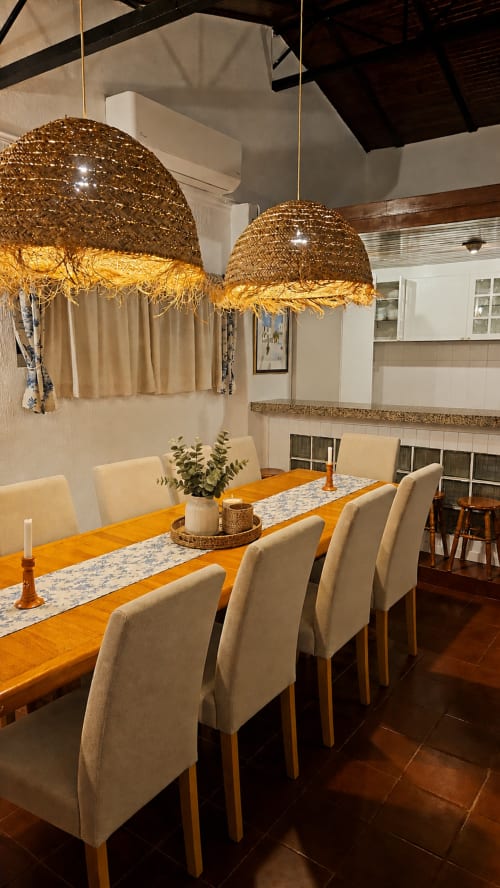 Sala de jantar elegante na quinta de Herdade da Cova da Onça em Canha com mesa de madeira, cadeiras creme e luminárias de palha