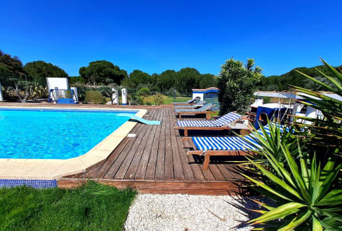 Área de piscina ensolarada na Herdade da Cova da Onça com deck de madeira, espreguiçadeiras e jardins verdejantes em Canha, Portugal