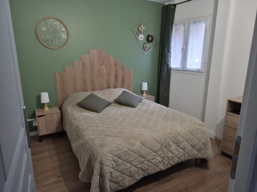 Dormitorio de la cabaña La Boiseline con cabecero de madera, ropa de cama acolchada beige y paredes verde salvia en Domaine en Terre Happy