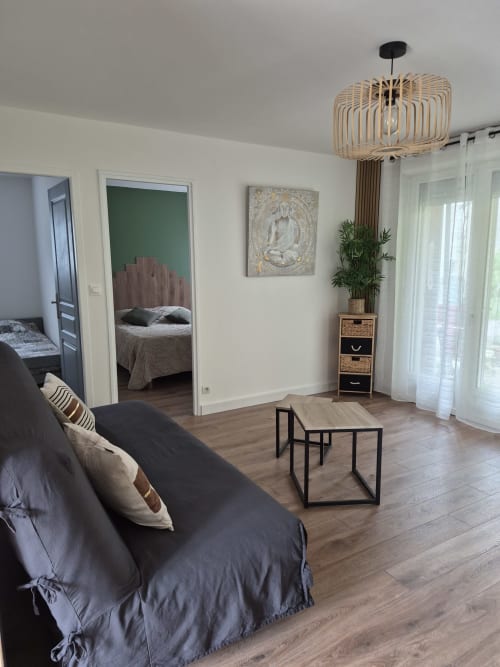 Acogedora sala de estar en Domaine en Terre Happy con sofá, mesa de centro y vista al dormitorio por la puerta