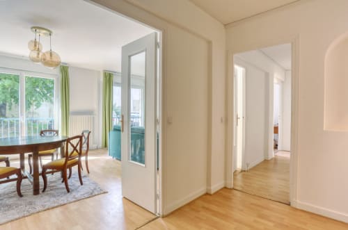Couloir lumineux dans un appartement de luxe à Versailles avec parquet, portes blanches et salle à manger vue jardin