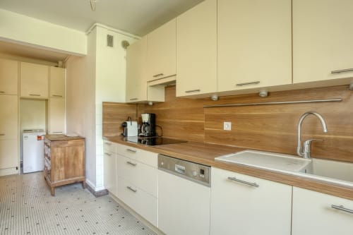 Cuisine moderne avec armoires crème, comptoirs en bois et appareils en acier inoxydable à Versailles Luxury Retreat