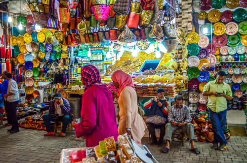 Étal coloré du souk de Marrakech exposant des assiettes en céramique, lanternes et artisanat traditionnel au Riad 191.