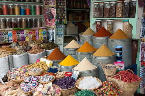 Étalage du marché aux épices au Riad 191 à Marrakech avec poudres colorées et ingrédients dans des récipients traditionnels