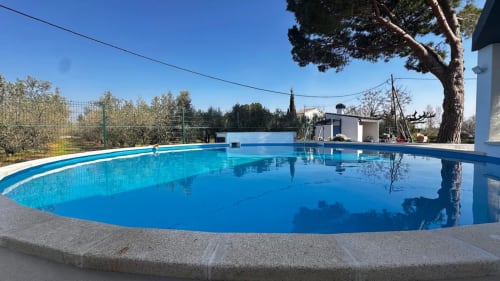 Amplia piscina redonda con agua azul cristalina en Apartaments Voramar de Cambrils, rodeada de terraza y vegetación