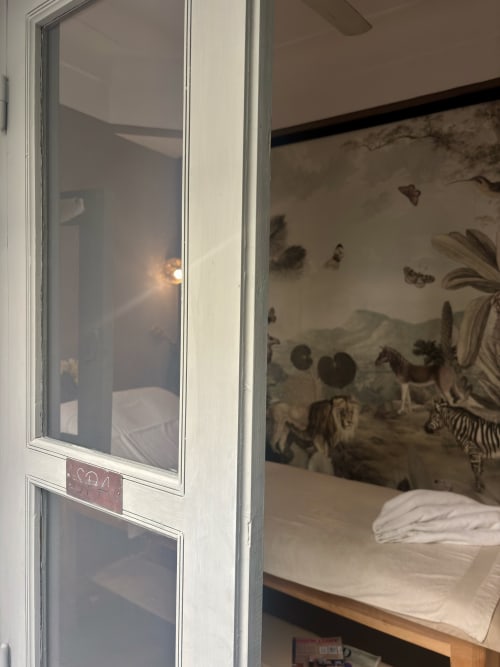 Chambre du Riad 191 avec papier peint jungle, literie blanche et porte vitrée à Marrakech