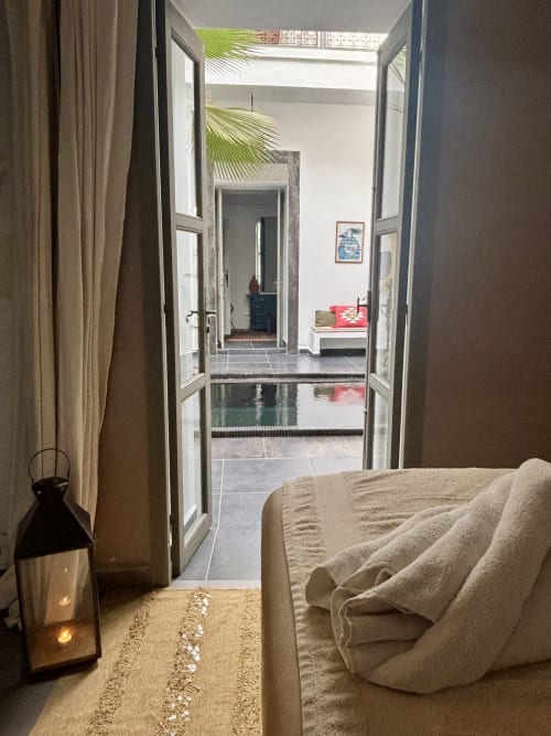 Chambre du Riad 191 avec portes ouvertes sur la cour, piscine et palmiers, Marrakech