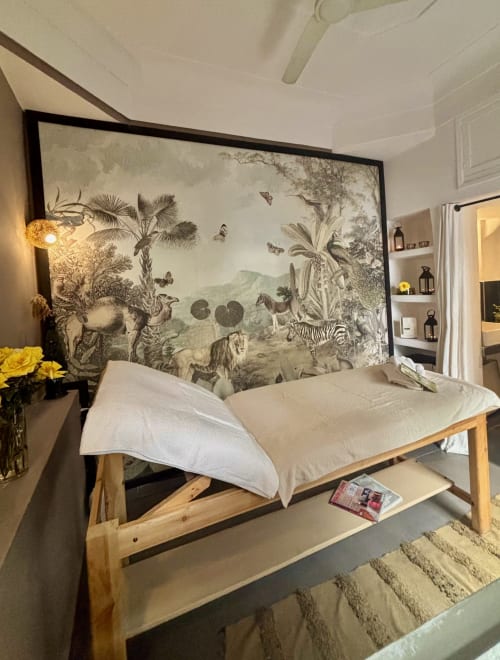 Chambre du Riad 191 Marrakech avec lit en bois, draps blancs et tête de lit décorée de fresques animalières