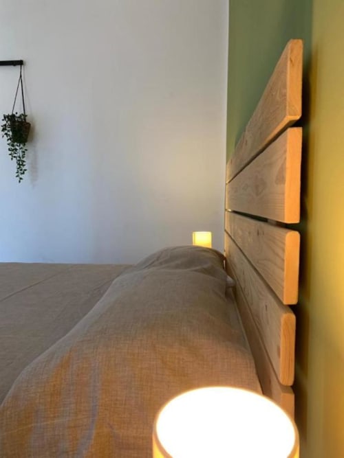 Camera moderna presso Cilento Rooms con testata in legno, illuminazione calda e pianta sospesa ad Agnone, Italia