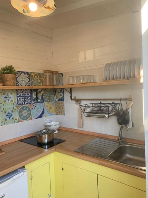 Luminosa cucina con mobili gialli, banconi in legno, piastrelle decorate, scaffali aperti e lavello presso Cilento Rooms ad Agnone